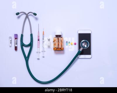 Télémédecine et équipement médical, stéthoscope connecté à un smartphone en ligne pour se connecter à un professionnel de santé et à une gamme de seringues et de médicaments. Banque D'Images