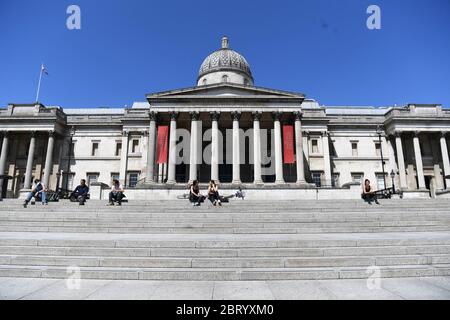RETRANSMETTANT LA DATE DE MODIFICATION les gens sont assis sur les marches au soleil à Trafalgar Square, Londres, après l'introduction de mesures pour mettre le pays hors de l'isolement. Banque D'Images