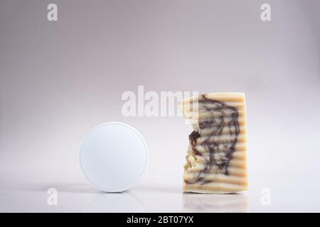 Un pot rond blanc de crème pour le visage ou le corps et du savon naturel fait main sur fond beige. Concept de peau de nature. Cosmétiques biologiques. Gros plan. Banque D'Images