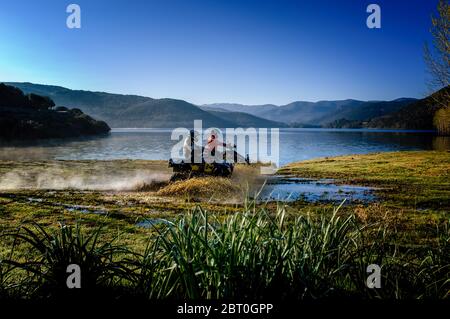 Deux personnes à vélo à travers des échaloes sur le lac de Gusana, un lac artificiel dans le territoire de Gavoi, Sardaigne, Italie. Banque D'Images