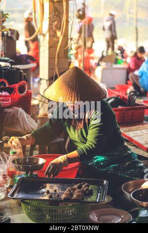 Hoi an, Vietnam - 7 février 2018 : attention douce sur la femme vietnamienne qui vend des aliments sur un marché en bord de route à Hoi an, province de Quang Nam, Vietnam. Banque D'Images