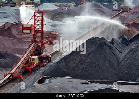 L'eau est priée sur le charbon et les tas de minerai au Hansaport dans le port de Hambourg. Hansaport est un terminal en vrac sec spécialisé dans la manutention du charbon et du minerai. Banque D'Images