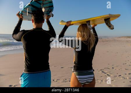 Couple caucasien tenant des planches de surf à la plage. Banque D'Images