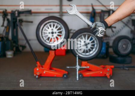 Clé auto mécanique pour porte-clés, entretien des pneus. Inspection professionnelle des pneus d'automobiles en atelier, roues sur vérins de levage, outils de réparation et équipements Banque D'Images