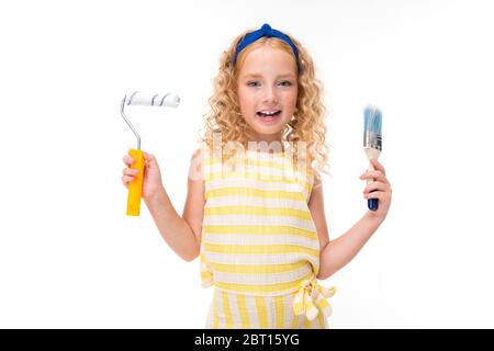 petite fille avec brosse et rouleau pour peindre les murs sur un fond blanc. Banque D'Images