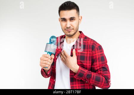 le présentateur masculin avec un microphone dans ses mains a un mal de gorge sur un fond blanc isolé de studio. Banque D'Images