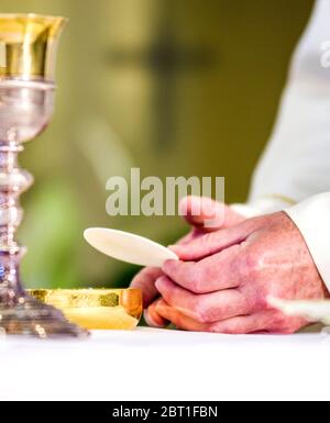 Pendant la célébration de la messe, les mains du prêtre, comme les mains du Pape François, consacrent l'hôte qui devient le corps du Christ Banque D'Images