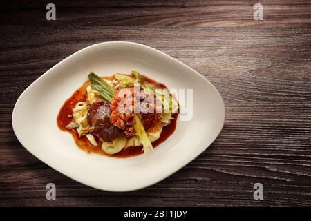 Directement au-dessus d'une nouvelle assiette de cuisine élégante de bœuf sur les légumes et la sauce sur fond de bois Banque D'Images