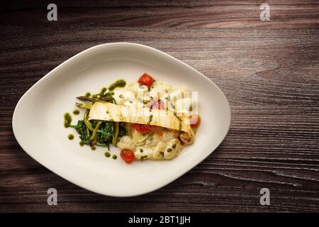 Directement au-dessus d'une élégante assiette de pâtes Nouvelle cuisine avec asperges et épinards sur fond de bois Banque D'Images