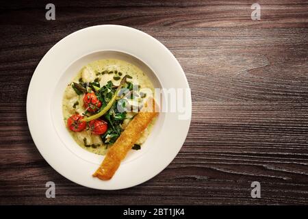 Directement au-dessus d'un élégant bol de soupe à la crème de légumes Nouvelle cuisine sur fond de bois Banque D'Images