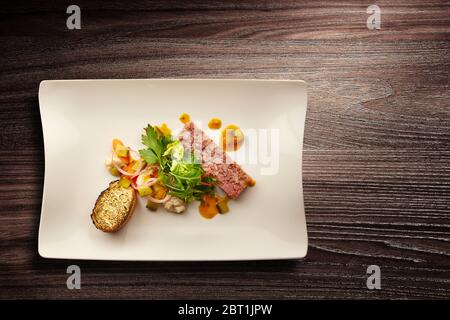 Directement au-dessus d'une élégante assiette de cuisine Nouvelle avec salade et pain sur fond de bois Banque D'Images