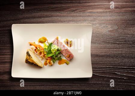 Directement au-dessus d'une élégante assiette de cuisine Nouvelle avec salade et pain sur fond de bois Banque D'Images