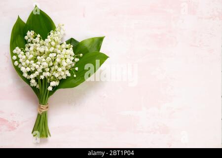 Bouquet de fleurs nénuphars de la vallée sur table rose, vue de dessus, espace pour le texte, platlay. Banque D'Images