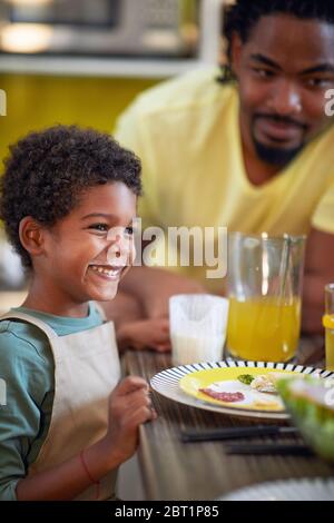 Joyeux garçon s'amuser au petit déjeuner avec son père et avoir la moustache du lait. Banque D'Images