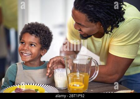 Joyeux garçon avec la moustache du lait au petit déjeuner chez son père. Banque D'Images