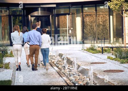 groupe de jeunes employés entrant dans le bâtiment d'affaires, revenant de la pause. Banque D'Images