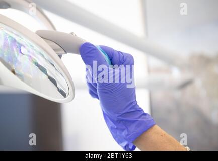 Éclairage mobile à main avec gants en nitrile bleu dans le bureau du dentiste Banque D'Images