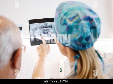 Vue arrière de l'homme anonyme et de la femme examinant le rayon X des dents tout en travaillant dans la clinique moderne ensemble Banque D'Images