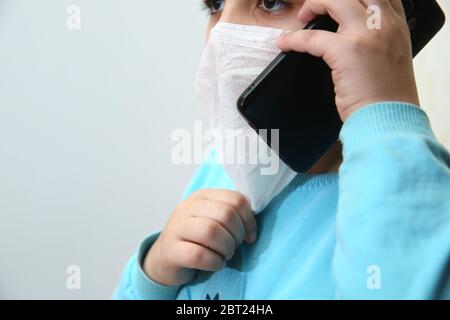 Bakou, Azerbaïdjan. 28.02.2020 . Petit homme d'affaires dans un costume d'affaires avec téléphone à la main. Un garçon masqué parle au téléphone. Protection contre la couronne Banque D'Images