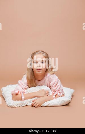 la fille blonde repose sur un fond rose sur des oreillers en fourrure Banque D'Images