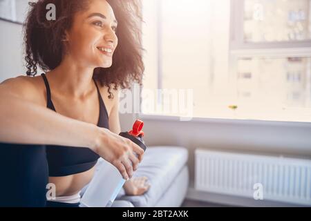 Mettre la fille dans des vêtements de sport assis sur le canapé Banque D'Images