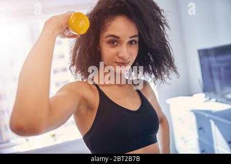 Femme sportive aux cheveux sombres qui s'efforce à la maison Banque D'Images