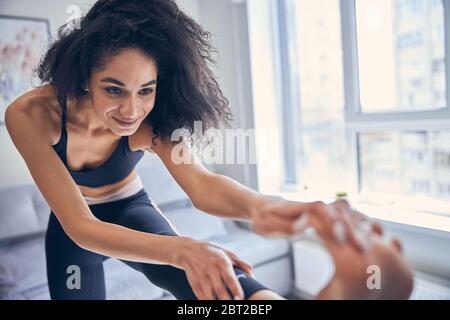 Femme souriante pratiquant le yoga à la maison Banque D'Images