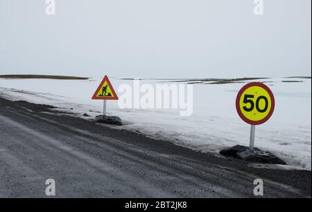 Route vide campagne route gelée avec neige en hiver et panneaux d'avertissement en Islande Banque D'Images