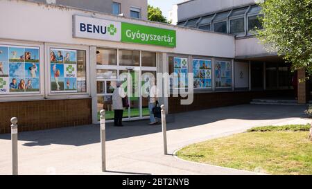 Gyor Hongrie 05 21 2020: Des clients âgés de sexe féminin attendent à l'entrée d'une pharmacie de Benu dans un masque protecteur en raison du coronavirus. Banque D'Images
