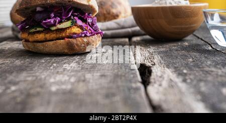 Vue en angle bas de délicieux hamburgers végétaliens faits de pois chiches avec courgettes, chou rouge et vinaigrette dans pain de levain maison. Banque D'Images