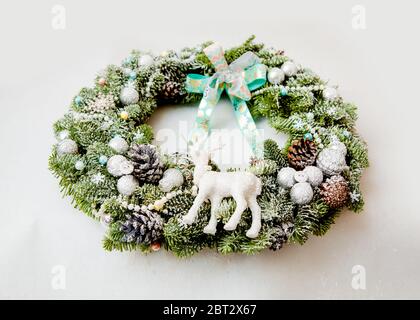 Couronne de Noël avec des cônes, des boules, arrosées de neige artificielle, décorées de rubans et une figure de cerf Banque D'Images