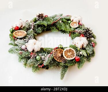 Couronne de Noël avec perles brillantes rouges, fleurs de coton et tranches d'oranges Banque D'Images