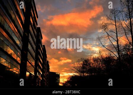 Un coucher de soleil enflammé se reflète sur un bâtiment d'une ville Banque D'Images