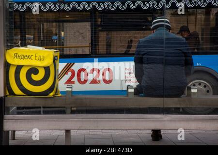 Moscou, Russie. 22 mai 2020 UN homme attend un bus à un arrêt sur fond d'un sac de messagerie d'un service de livraison de nourriture 'Yandex EDA' dans le centre de la ville de Moscou, Russie Banque D'Images