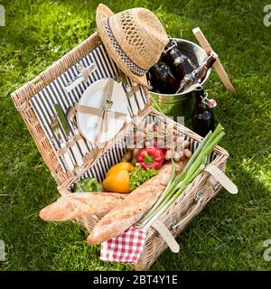 Végétarien et Végétalien Santé avec déjeuner pique-nique salade fraîche ingrédients et baguettes placées dans un panier en osier à côté d'un refroidisseur à vin en argent Banque D'Images