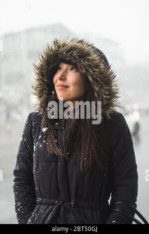 Portrait d'une femme souriante dans une parka bordée de fourrure debout dans la neige, Itaewon, Corée du Sud Banque D'Images