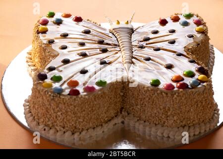 Gâteau au fromage de vanille en forme de papillon avec garniture de caramel coloré crème glacée au moka sur une base argentée Banque D'Images