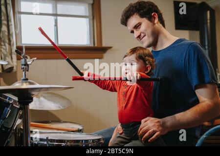 Père enseignant bébé garçon à jouer batterie. Parent avec enfant en bas âge s'amuser, passer du temps ensemble. Papa et enfant jouant de la musique. Activité de loisir en famille Banque D'Images