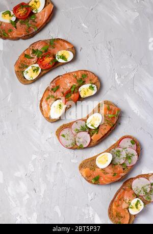 Plat de collation saine. Sandwichs - oeuf de caille, tomates cerises, fromage de chèvre, pois verts, radis. Concept minimal. Photo verticale Banque D'Images