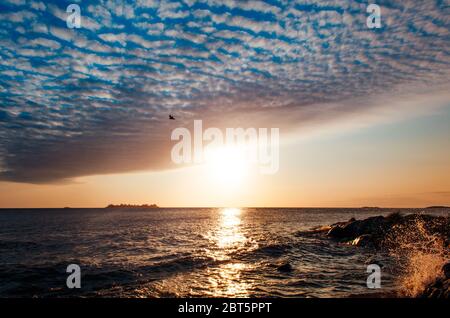 Une capture à couper le souffle de l'heure d'or à Colonia Del Sacramento, en Uruguay avec une vue sur le Rio de la Plata et une seule vague se brisant dans les rochers. Banque D'Images