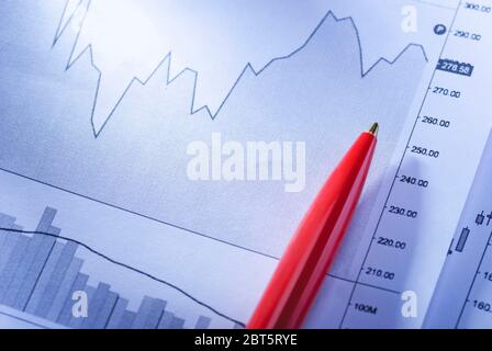 Stylo rouge sur les graphiques statistiques d'entreprise montrant les fluctuations de performance ou les projections sur les graphiques à barres et linéaires en gros plan Banque D'Images