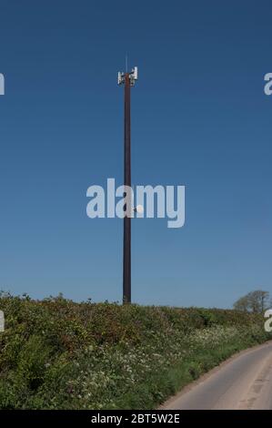 Mât de téléphone mobile avec antennes et un émetteur et récepteur large bande sur une voie de campagne tranquille avec un ciel bleu vif à l'arrière-plan rural Devon Banque D'Images