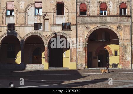 Bologne, Italie - Mai 21 2020:Homme avec masque à protéger contre le covid (coronavirus) prend un chien pour une promenade dans la Piazza Santo Stefano touristique, avec le salut Banque D'Images