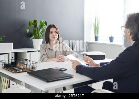 Une cliente brunette sérieuse de psychologue le regardant pendant la discussion de ses problèmes, assis au bureau Banque D'Images