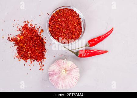 Assaisonnement à la Harissa dans une assiette de verre, ail frais et deux piments Banque D'Images