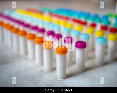 Flacons en plastique coloré remplis de comprimés homéopathiques blancs/globules Banque D'Images