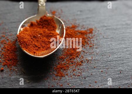 Une cuillère à café de paprika ou de poivre de Cayenne sur fond d'ardoise. Ingrédients crus pour la cuisson Banque D'Images