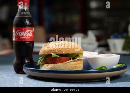 Un hamburger maison servi avec un coca et un bol de sauce tomate et des tranches de concombre Banque D'Images