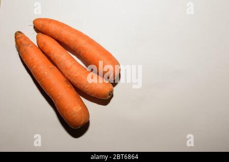 Photo aérienne d'un groupe de trois carottes fraîches sur fond blanc Banque D'Images