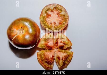 Une paire de tomates fraîches de Kumato ouvre en deux et hachée sur fond blanc Banque D'Images